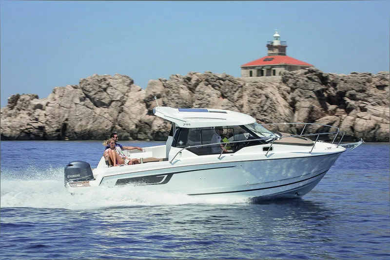 The Image of 2025 Jeanneau NC 795 cruising near rocky coastline with lighthouse in background. - 1