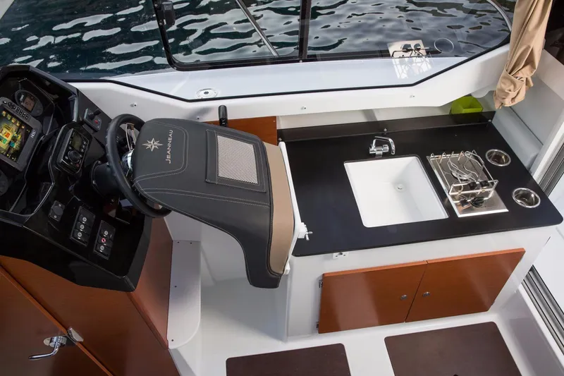 Slide: The Image of 2025 Jeanneau NC 795 boat interior with steering console and kitchenette. - 14