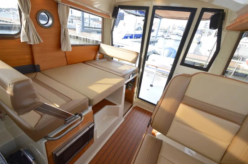 Slide: The Image of Interior of 2020 Ranger Tugs R-27 boat with beige seating and wood accents. - 16