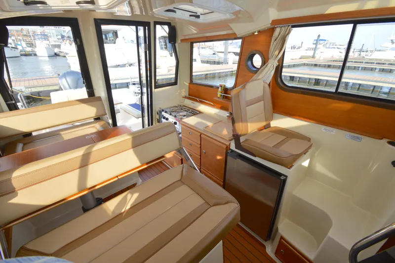 Slide: The Image of Interior of 2020 Ranger Tugs R-27 boat with seating, kitchenette, and marina view. - 17
