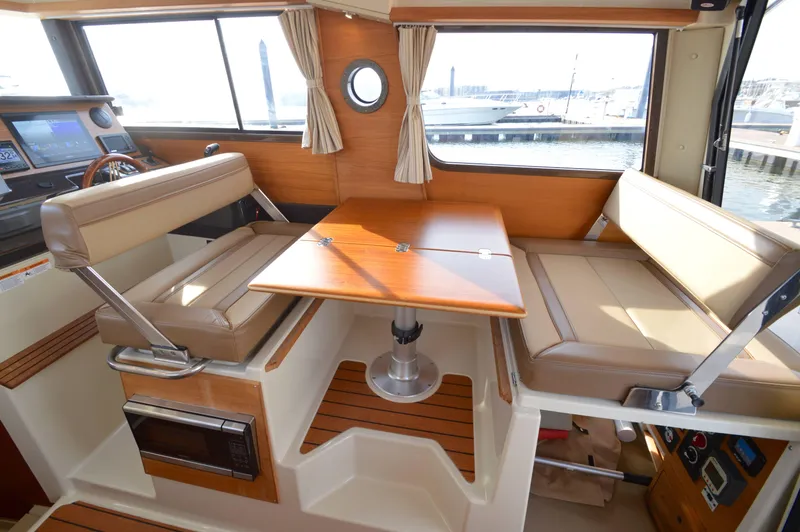 Slide: The Image of Interior of 2020 Ranger Tugs R-27, featuring a cozy dining area with beige seating. - 19