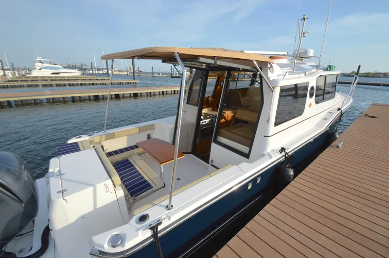 Slide: The Image of 2020 Ranger Tugs R-27 docked, featuring spacious deck and seating area. - 2