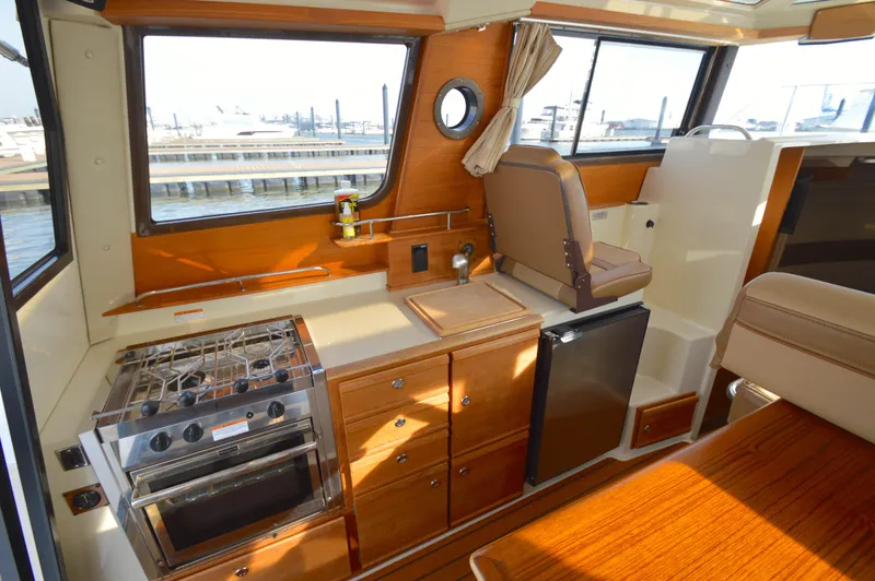 Slide: The Image of Interior of 2020 Ranger Tugs R-27 with kitchen, stove, and seating area. - 21