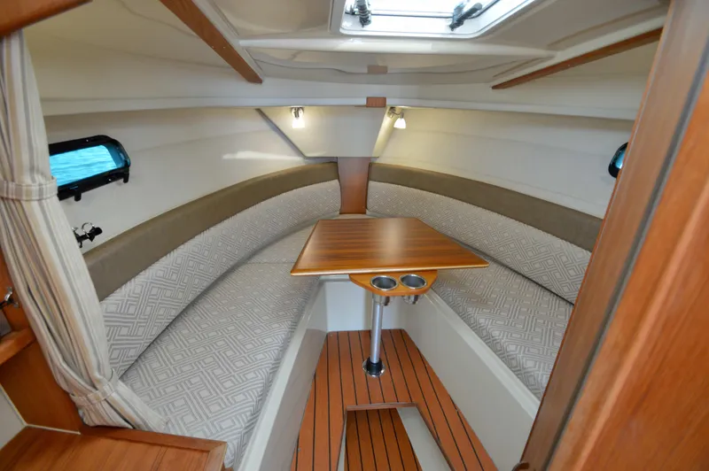 Slide: The Image of 2020 Ranger Tugs R-27 cabin interior with wood table and cushioned seating. - 24