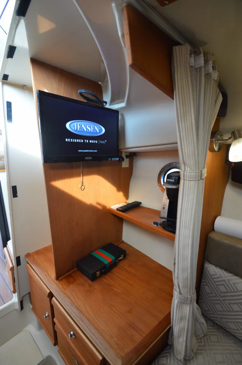 Slide: The Image of 2020 Ranger Tugs R-27 interior with TV, wooden cabinetry, and cozy seating area. - 25