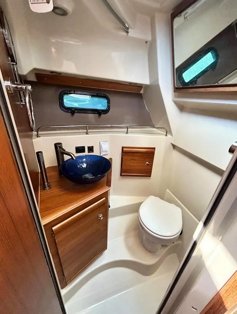 Slide: The Image of 2020 Ranger Tugs R-27 bathroom with modern sink, toilet, and wooden cabinetry. - 28