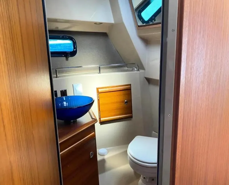 Slide: The Image of 2020 Ranger Tugs R-27 boat bathroom with blue sink and wooden cabinetry. - 29