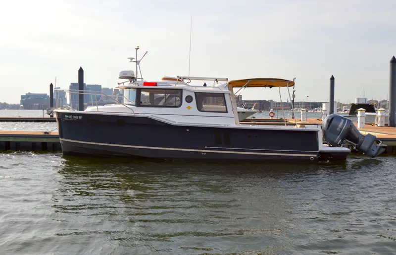 Slide: The Image of 2020 Ranger Tugs R-27 boat docked at a marina with outboard motor. - 42
