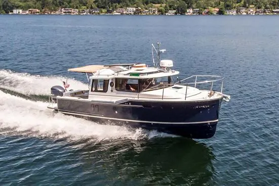 Slide: The Image of 2020 Ranger Tugs R-27 cruising on a lake with scenic shoreline in the background. - 43