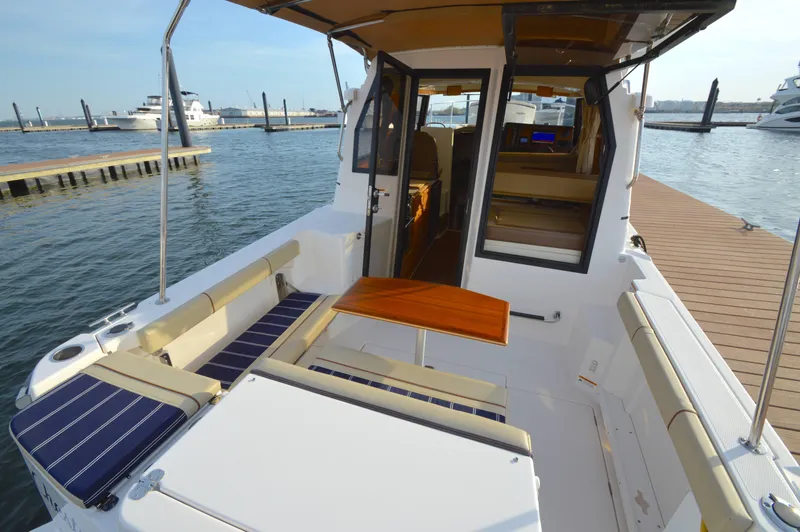 Slide: The Image of 2020 Ranger Tugs R-27 boat interior with seating and table at a marina dock. - 9