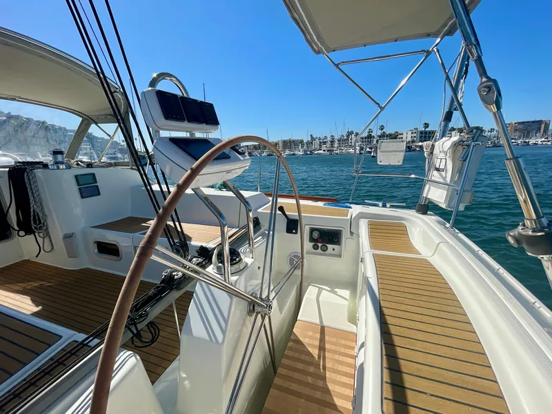 Slide: The Image of Beneteau First 47.7 sailboat cockpit with wooden deck, marina view, sunny day, 2002 model. - 13