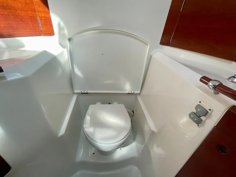 Slide: The Image of Beneteau First 47.7 2002 yacht bathroom with white toilet and wooden accents. - 32