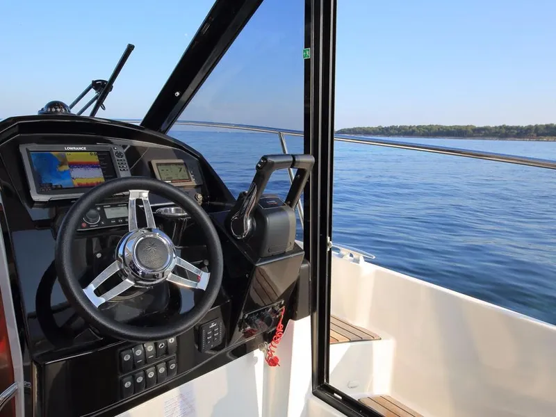 Slide: The Image of 2024 Jeanneau NC 895 helm with navigation system, steering wheel, and ocean view. - 16