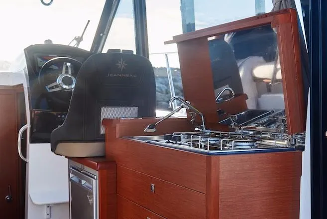 Slide: The Image of 2024 Jeanneau NC 895 boat interior with helm, sink, and stove. - 9