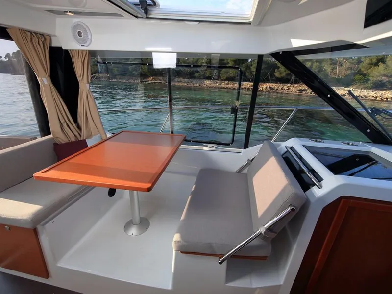Slide: The Image of 2024 Jeanneau NC 895 interior with dining area, large windows, and scenic water view. - 12