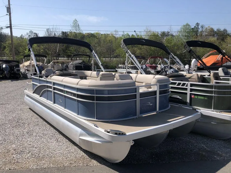 Slide: The Image of 2018 Bennington 22SLX pontoon boat with canopy, parked on gravel lot. - 1