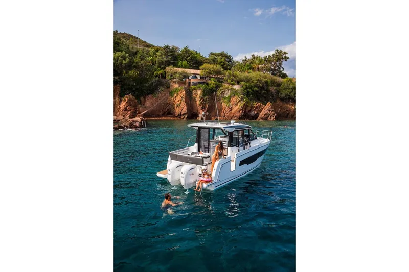 Slide: The Image of 2025 Jeanneau NC 895 Series 2 boat anchored near scenic rocky coastline. - 23