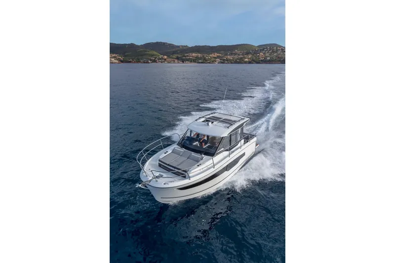 Slide: The Image of 2025 Jeanneau NC 895 Series 2 cruising on open water, scenic coastal backdrop. - 46