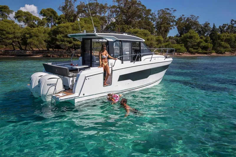 Slide: The Image of 2025 Jeanneau NC 895 Series 2 boat on clear turquoise water near a forested shoreline. - 54