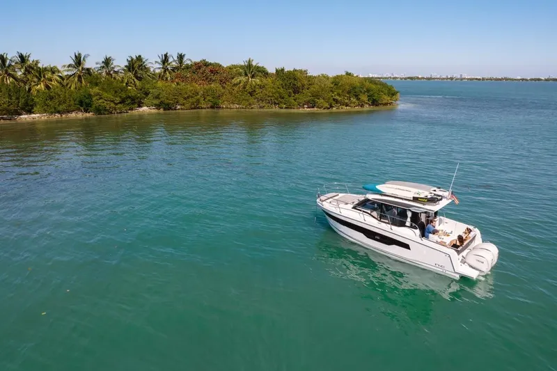 Slide: The Image of 2025 Jeanneau NC 895 Series 2 cruising on serene tropical waters near lush island. - 77