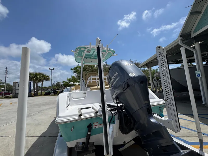 Slide: The Image of 2023 Sportsman Open 212 Center Console boat with outboard motor in a sunny marina. - 17