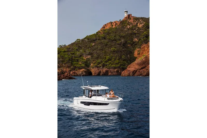 Slide: The Image of 2025 Jeanneau NC 895 Series 2 cruising near rocky coastline with lighthouse. - 20