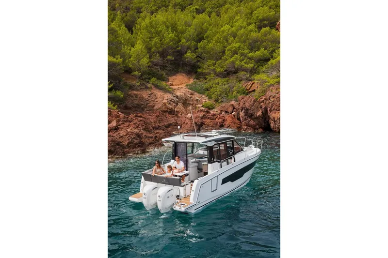 Slide: The Image of 2025 Jeanneau NC 895 Series 2 boat cruising near rocky coastline with lush greenery. - 21