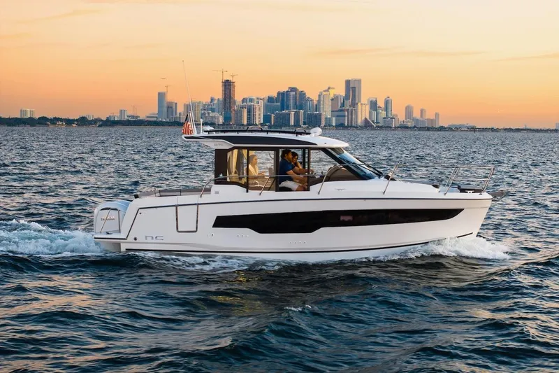 Slide: The Image of 2025 Jeanneau NC 895 Series 2 cruising on water with city skyline at sunset. - 66