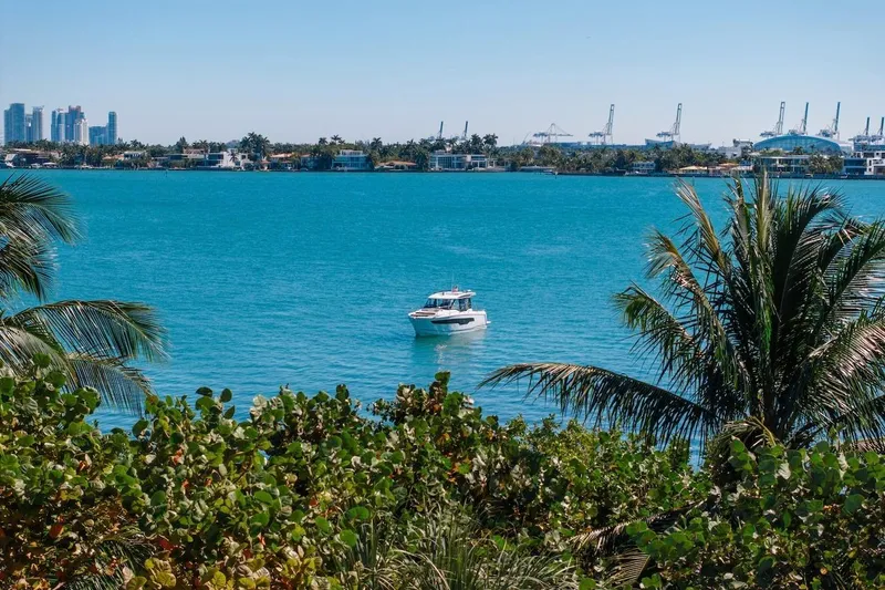 Slide: The Image of 2025 Jeanneau NC 895 Series 2 boat on turquoise water, with city skyline and palm trees. - 81