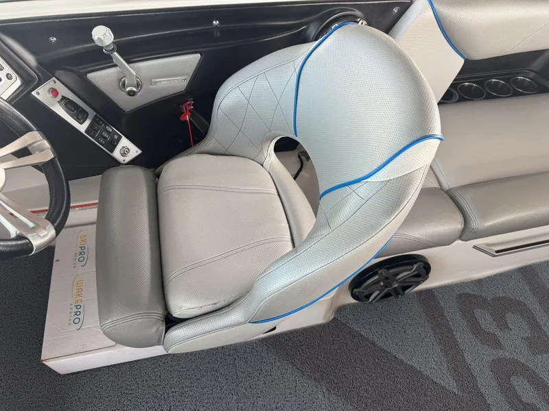 Slide: The Image of 2015 MasterCraft X23 boat interior with gray and blue seating, steering wheel, and control panel. - 22