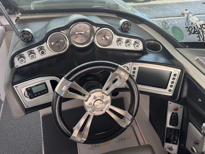 Slide: The Image of 2015 MasterCraft X23 boat dashboard with steering wheel, gauges, and control panel. - 24