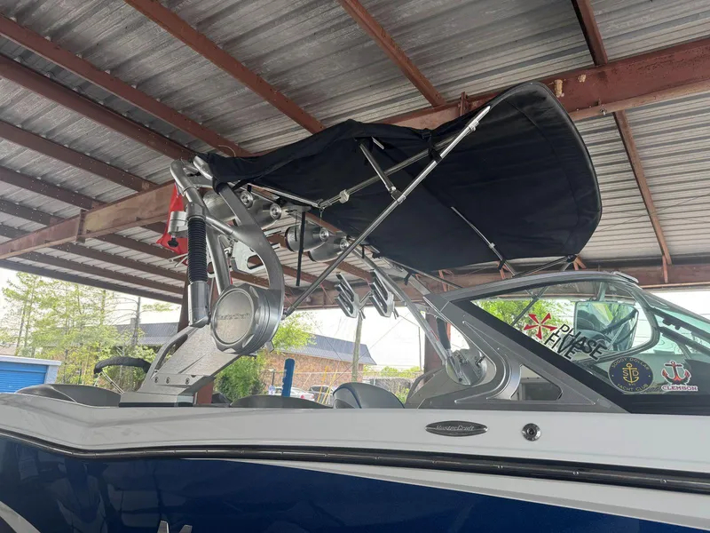 Slide: The Image of 2015 MasterCraft X23 boat under a metal roof, featuring a sleek design and black canopy. - 5