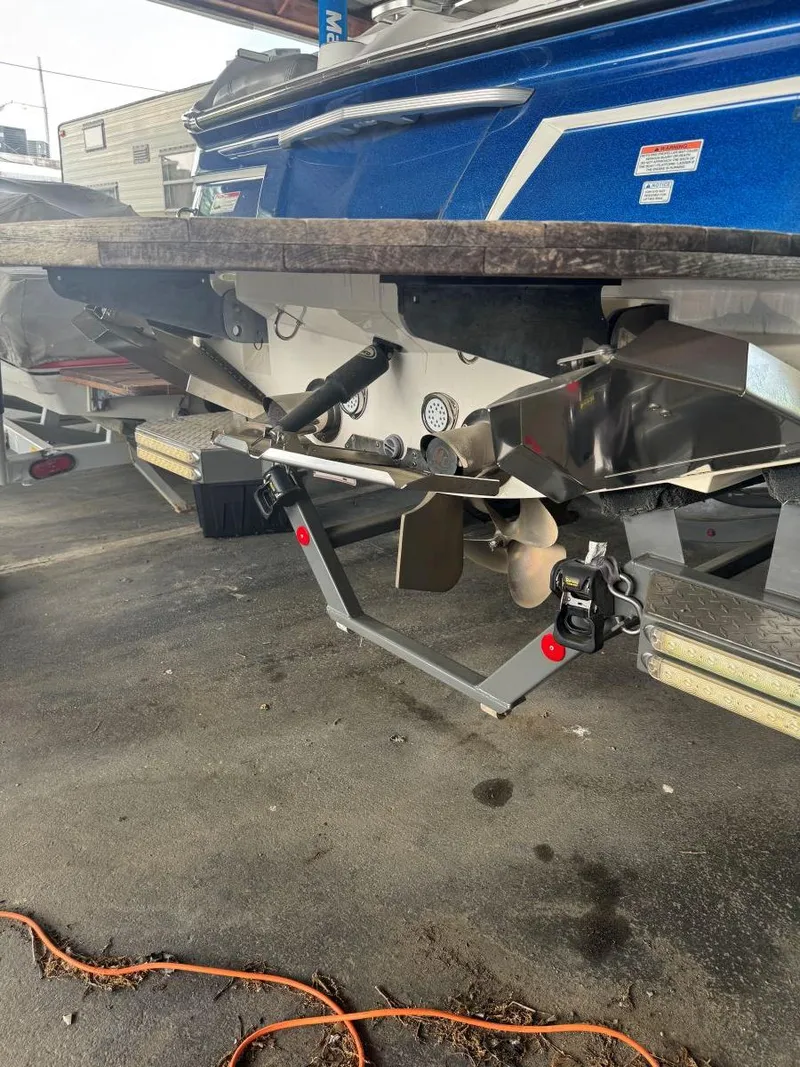 Slide: The Image of 2015 MasterCraft X23 boat stern with propeller and wakeboard tower, parked on concrete. - 8