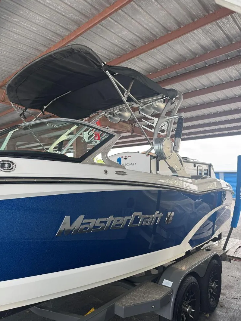Slide: The Image of 2015 MasterCraft X23 boat with blue hull under a metal roof. - 9