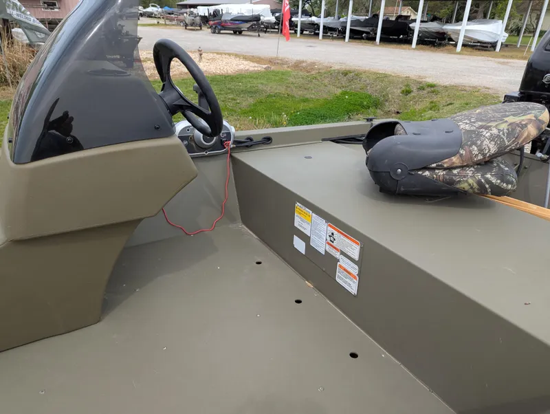 Slide: The Image of 2022 Tracker Grizzly 1648 SC boat interior with steering wheel and camo seat. - 38