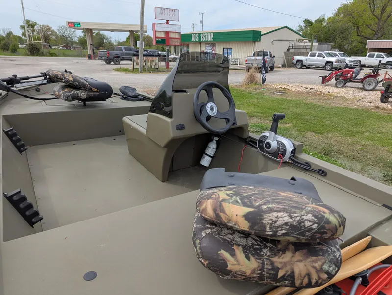 Slide: The Image of 2022 Tracker Grizzly 1648 SC boat with camo seats, parked near a store. - 39