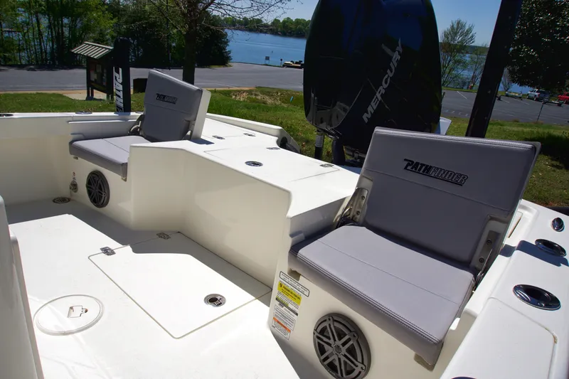 Slide: The Image of 2025 Pathfinder 2500 Hybrid boat interior with cushioned seats and speakers, near a lake. - 18
