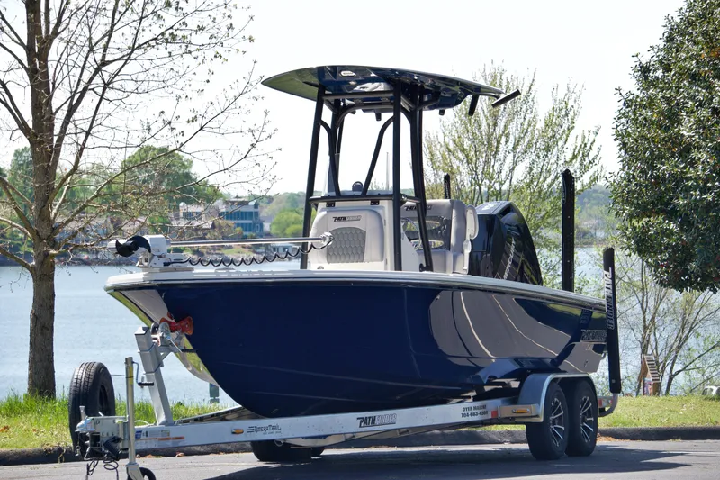 Slide: The Image of 2025 Pathfinder 2500 Hybrid boat on trailer by a lake, showcasing sleek design and modern features. - 2