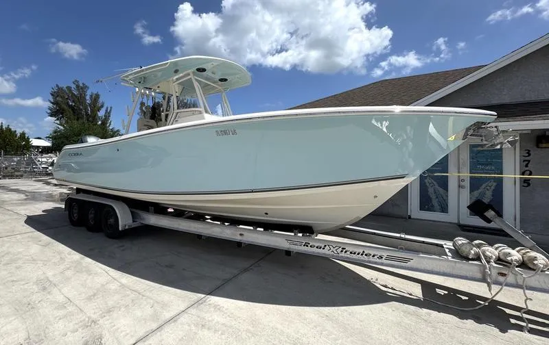 The Image of 2016 Cobia 296 Center Console boat on trailer, parked outdoors under blue sky. - 0