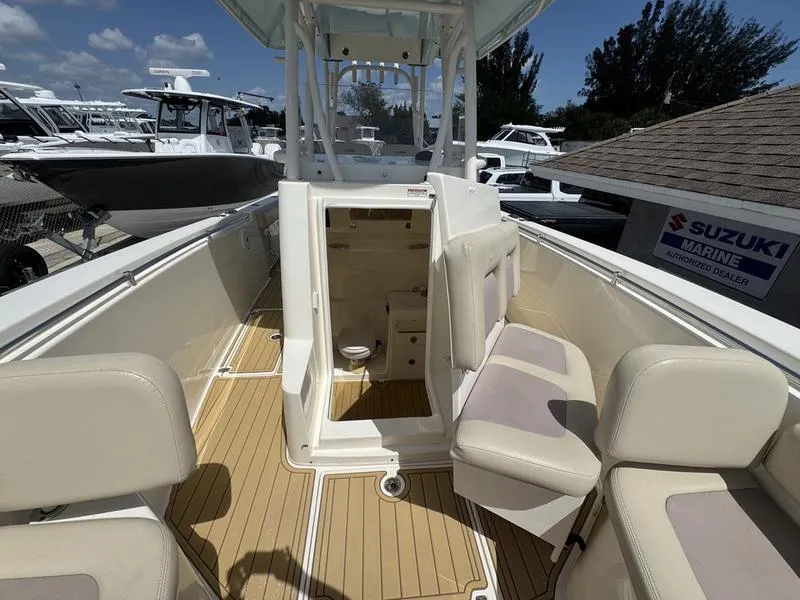 Slide: The Image of 2016 Cobia 296 Center Console boat interior with beige seating and wood flooring. - 11