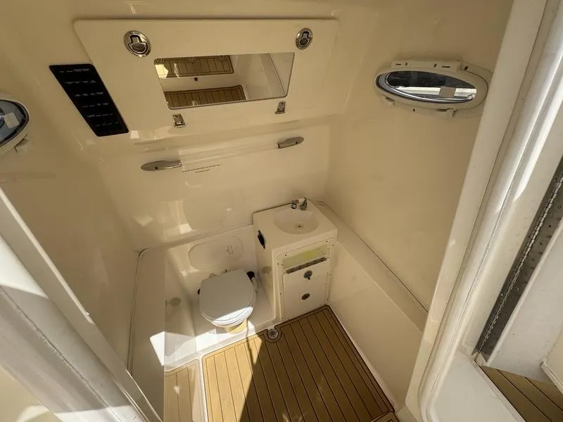Slide: The Image of 2016 Cobia 296 Center Console boat bathroom with sink, toilet, and wooden flooring. - 14