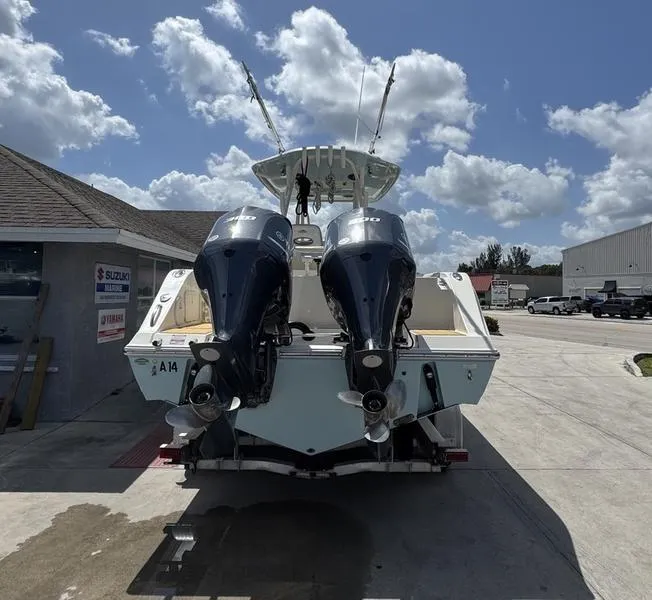 Slide: The Image of 2016 Cobia 296 Center Console boat with dual outboard motors, parked outdoors. - 2