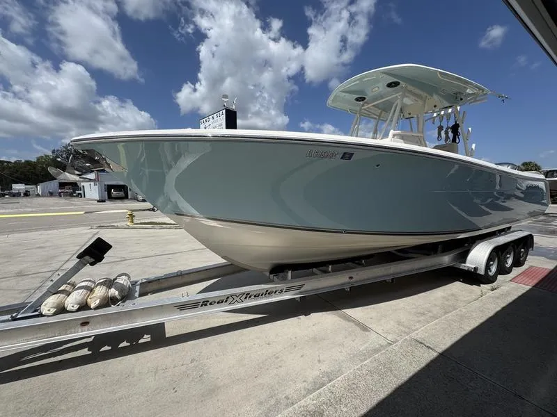 Slide: The Image of 2016 Cobia 296 Center Console boat on trailer under a partly cloudy sky. - 3