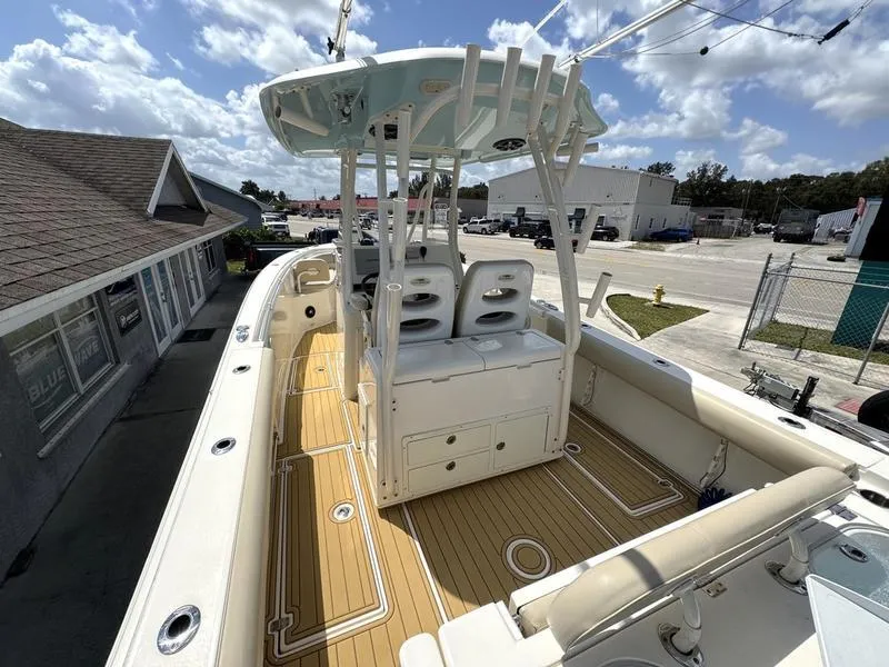 Slide: The Image of 2016 Cobia 296 Center Console boat with spacious deck and seating, docked under a sunny sky. - 5