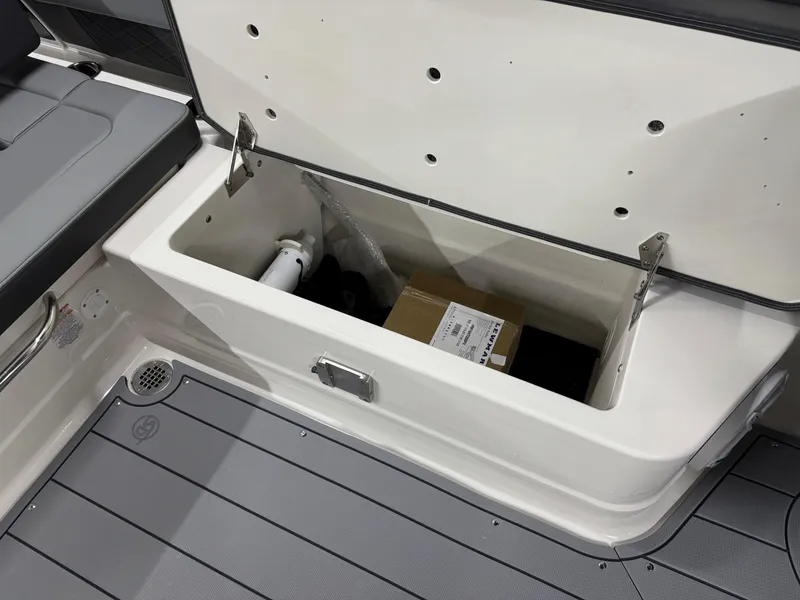 Slide: The Image of 2025 Chaparral 2870 SSX boat storage compartment with open lid and visible contents. - 35