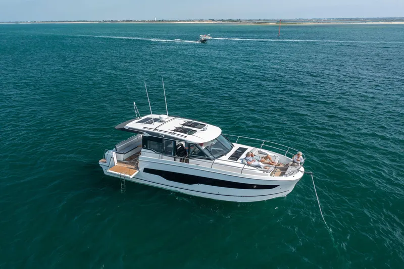 Slide: The Image of 2025 Jeanneau NC 1295 Coupe cruising on open water with passengers relaxing on deck. - 5