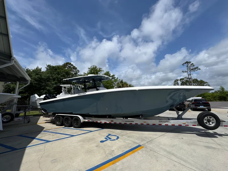 Slide: The Image of 2021 Fountain 38TE boat on trailer, parked outdoors under a partly cloudy sky. - 10