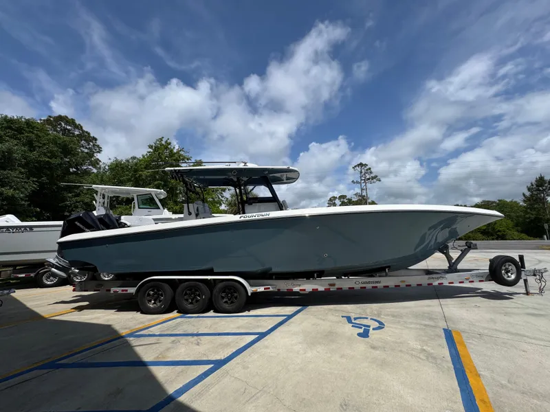 Slide: The Image of 2021 Fountain 38TE boat on trailer, parked outdoors under a cloudy sky. - 11