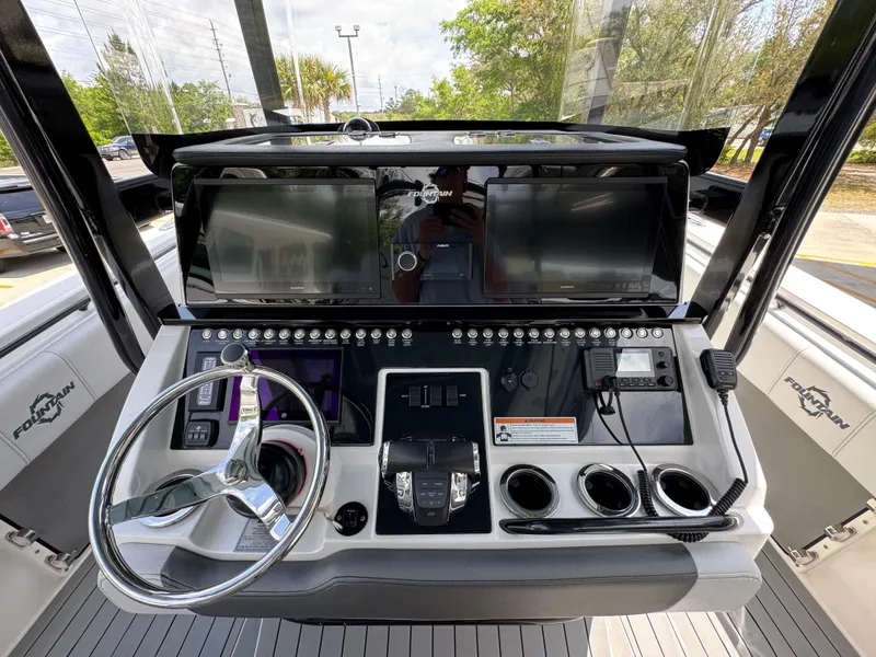 Slide: The Image of 2021 Fountain 38TE boat dashboard with steering wheel, controls, and dual screens. - 33