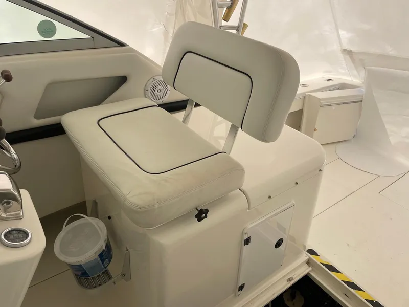 Slide: The Image of Captain's seat on 2000 Wellcraft 330 Coastal boat, featuring white upholstery and storage compartment. - 16